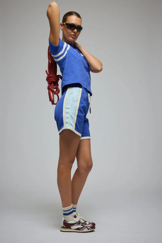 Person wearing a blue tracksuit with white accents on a gray background