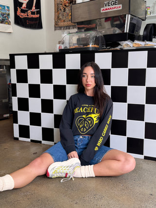 Woman sitting on the floor in front of a checkered wall with a counter in the background